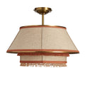 **Suspension en tissu beige avec finition frangée et bordure cuivrée**